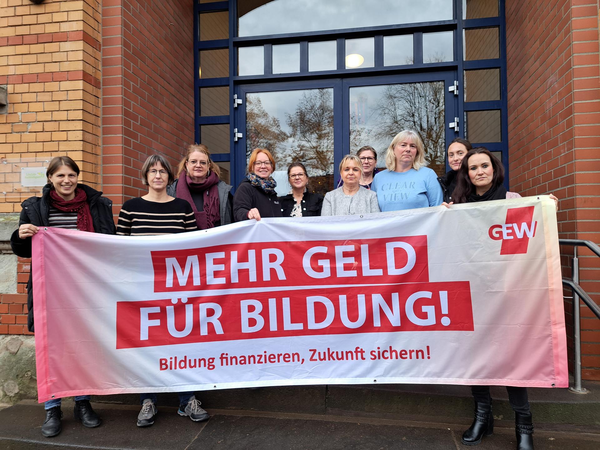 Eine diverse Gruppe von Menschen h&auml;lt einen Daumen nach oben in die Kamera.